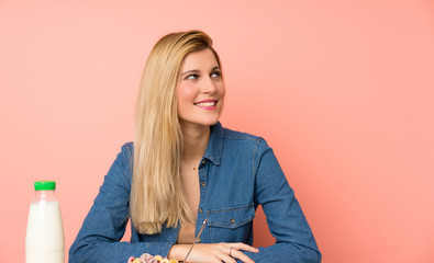 Wall Mural - Young blonde woman with bowl of cereals laughing and looking up