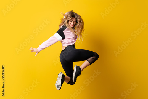 Urban Ballerina dancing over isolated yellow background and jumping Fotobehang