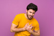 © luismolinero - Handsome over isolated purple wall having a pain in the heart