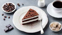Tiramisu Cake With Chocolate Decotaion On A Plate With Cup Of Coffee. Grey Stone Background.