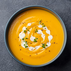 Wall Mural - Pumpkin, carrot cream soup in a bowl. Slate background. Close up. Top view.