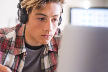 caucasian teenager indoor doing homework on the table at home - blonde guy writing and reading in hi