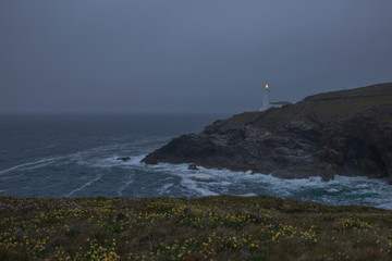 Wall Mural - lighthouse by the ocean on a gloomy evening on cornwalls north coast, uk
