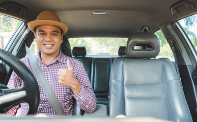 Young handsome asian man showing thumb up while driving car to travel.