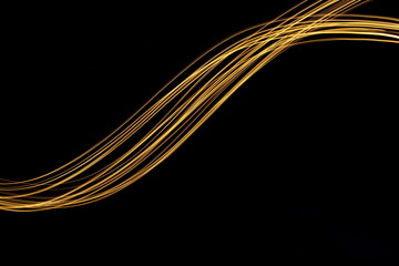 Wall Mural - Long exposure, light painting photography.  Vibrant streaks of metallic gold colour against a black background