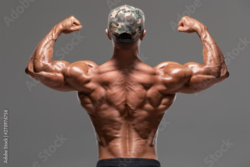 Obraz na plátne  Rear view muscular man showing back muscles and biceps, isolated on the gray background