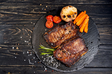 Wall Mural - juicy piece of fried meat lies on a stone plate against a black wooden table