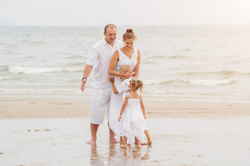 Wall Mural - Happy young family on the sunset at the beach.