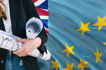 Tuvaluan Architect woman holding blueprint against Tuvalu waving flag background. Construction and architecture concept.