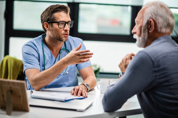 Wall Mural - Male doctor communicating with senior patient during medical consultations at his office.