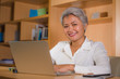 © TheVisualsYouNeed - natural lifestyle office portrait of attractive and happy successful mature Asian woman working at laptop computer desk smiling confident in entrepreneur success