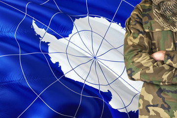 Crossed arms soldier with national waving flag on background - Antarctica Military theme.