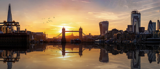 Fototapete - Weites Panorama der Skyline von London mit der Tower Brücke und der City bei Sonnenuntergang mit Reflektionen in dem Fluss Themse, Großbritannien