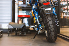 The Rear Of The Classic Motorcycles Standing In Repair Shop With Soft-focus And Over Light In The Background