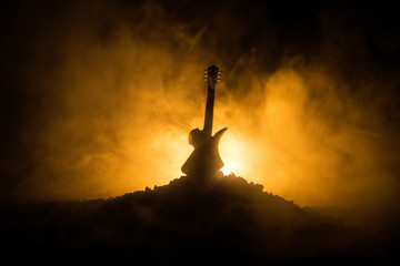 Wall Mural - Music concept. Acoustic guitar isolated on a dark background under beam of light with smoke with copy space. Guitar Strings, close up. Selective focus. Fire effects. Surreal guitar