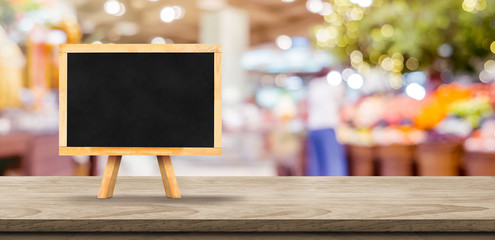 Aufkleber - Blank blackborad on wooden table top with blur people shopping at supermarket bokeh background,Mock up for display or montage of design.