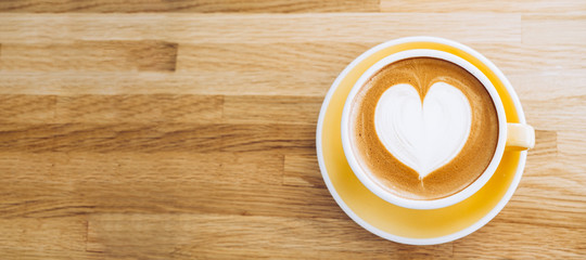 Top view of hot cappuccino coffee cup on wooden tray with heart latte art on wood table at cafe,Banner size food and drink concept.leave copy space for adding text.