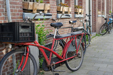 Old Long Red Vintage Bike With Two Seats More Behind The Driver And Big Plastic Box In Front Of Him. Street View In Amsterdam, Netherlands.