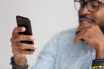 Close up happy smiling african-american man texting online using mobile