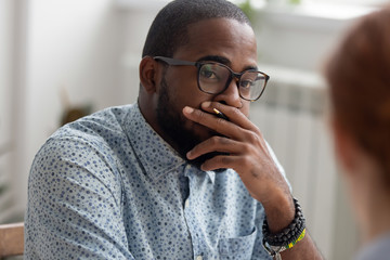 Unpleasantly surprised african-american businessman listening female caucasian coworker