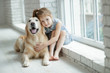 © nuzza11 - A child with an animal. Little girl with a dog at home.