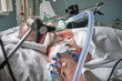 Intubated adult white man under ventilator lying in coma in intensive care department. Patient in critical state.