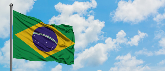 Wall Mural - Brazil flag waving in the wind against white cloudy blue sky. Diplomacy concept, international relations.