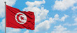 Tunisia flag waving in the wind against white cloudy blue sky. Diplomacy concept, international relations.