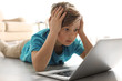 © New Africa - Shocked little child with laptop on floor indoors. Danger of internet