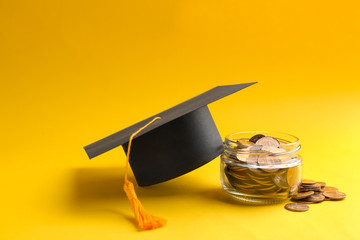 Wall Mural - Glass jar, coins and graduation hat on color background. Space for text