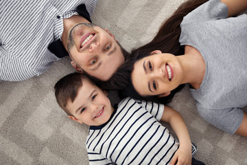 Poster - Happy parents and their son lying together on floor, view from above. Family time