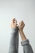 Woman taking off grey knitted sweater on light background, focus on hands