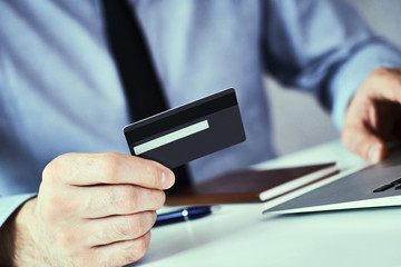 Businessman holding credit card and typing on laptop for online shopping and payment makes a purchase on the Internet.