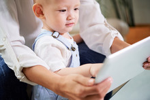 Mother Showing Tablet Computer With Kids Application To Her Curious Little Baby Boy