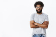© Cookie Studio - Studio shot of unimpressed calm and indifferent handsome adult african american bearded guy in glasses crossing hands over chest and looking careless at camera, not interested in conversation