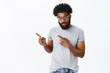 © Cookie Studio - Portrait of serious-looking handsome african american boyfriend with curly hair and beard in glasses looking strict at camera as waiting for answer pointing at upper left corner being concerned