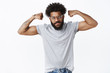 © Cookie Studio - Portrait of good-looking self-satisfied african american guy working out being strong and masculine showing off biceps with raised hands looking serious and challenging at camera as inviting to gym