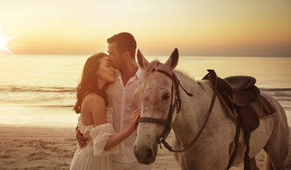 Young couple walking a majestic horse - seaside landscape