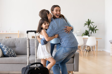 Excited mom and daughter hug welcome father home