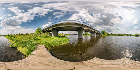 Wall Mural - full seamless spherical hdri panorama 360 degrees angle view on wooden pier of shore of wide river near bridge in sunny day with clouds in equirectangular projection, ready VR AR content
