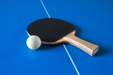 A tennis racket and a ball on the table. A sport game.