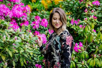 style woman near rhododendron flowers in a grarden in spring time