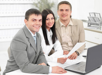 employees discussing financial charts sitting at their Desk