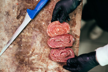 Wall Mural - Closeup on butcher's hands in gloves working in butchery.