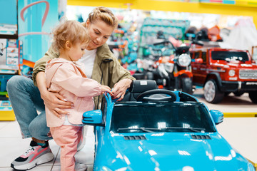 Poster - Mother with girl choosing electromobile in store