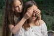 © Aleksandr - Warm family relations between mother and daughter. Girl is closing her mother eyes in the park.