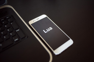 programming language lua for mobile development, concept. smartphone near the laptop