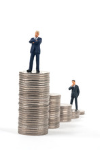 Two Miniature Businessmen Standing On Coin Stacks 