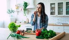 Beautiful Young Woman Is Preparing Vegetable Salad In The Kitchen. Healthy Food. Vegan Salad. Diet. Dieting Concept. Healthy Lifestyle. Cooking At Home. Prepare Food. Cutting Ingredients On Table