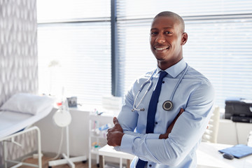 Wall Mural - Portrait Of Smiling Male Doctor With Stethoscope Standing By Desk In Office